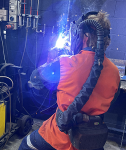 man in safety gear welding a mig weld on a post