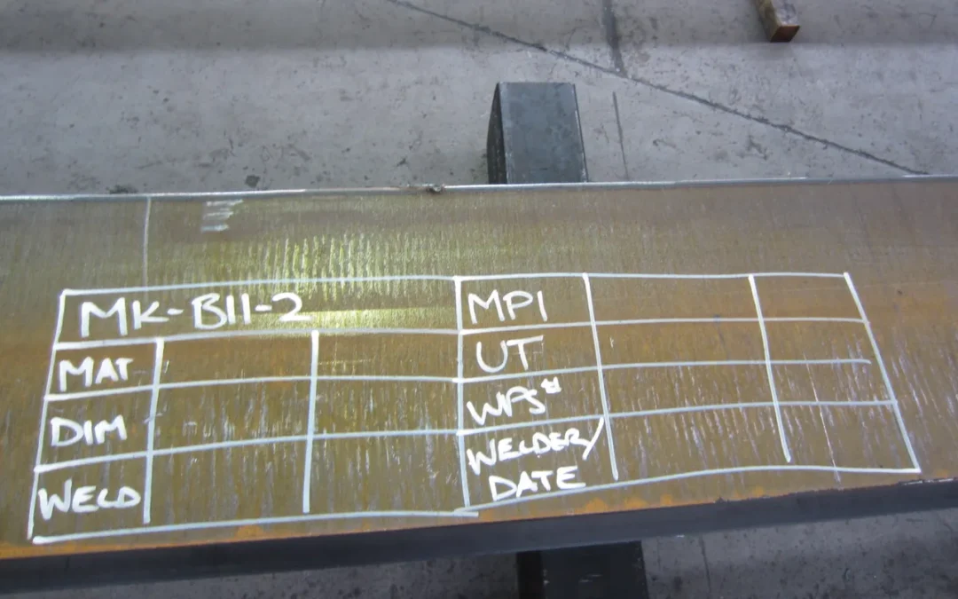 Chalk inspection grid on a fabricated steel member recording weld, dimension, material, WPS, welder, UT and MPI checks